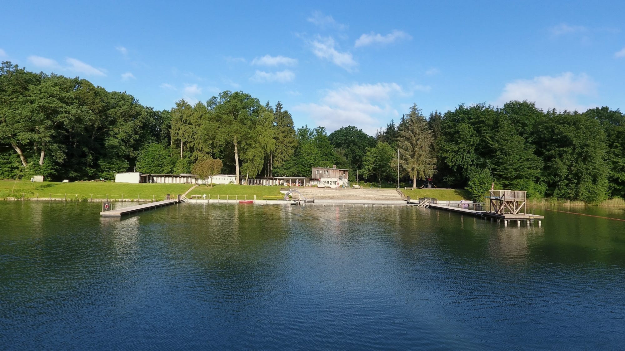 Blick auf Wasser, Sprungturm und Liegewiese des Tonteichs